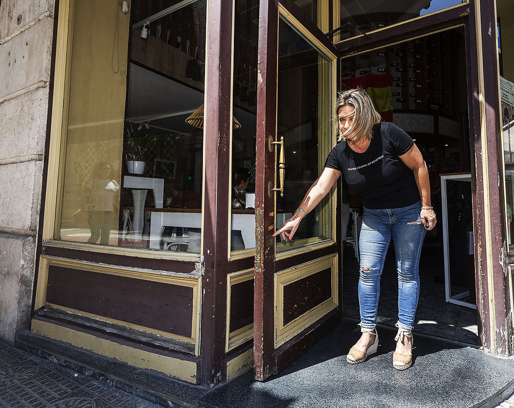 Ana, la propietaria, muestras los daños que los ladrones causaron ayer a la puerta del local.