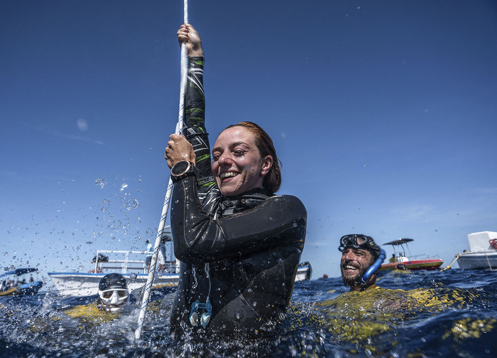 La apneísta burgalesa emerge del agua rodeada de los responsables de seguridad de las pruebas. 