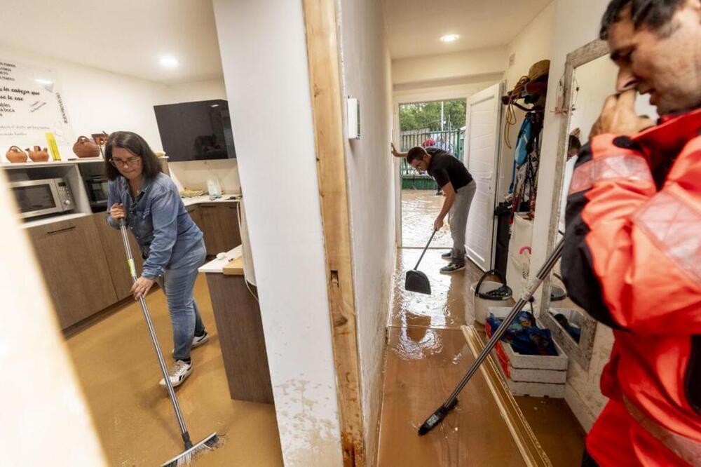 Cristina y Emilio, con la ayuda de uno de los bomberos de Aranda, luchaban por sacar todo el agua que inundaba su vivienda tras la tromba de agua caída en Castrillo de la Vega.