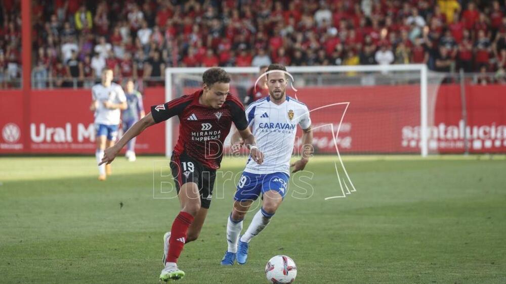 El centrocampista del Mirandés Mathis Lachuer conduce el balón perseguido por un jugador del Real Zaragoza. 