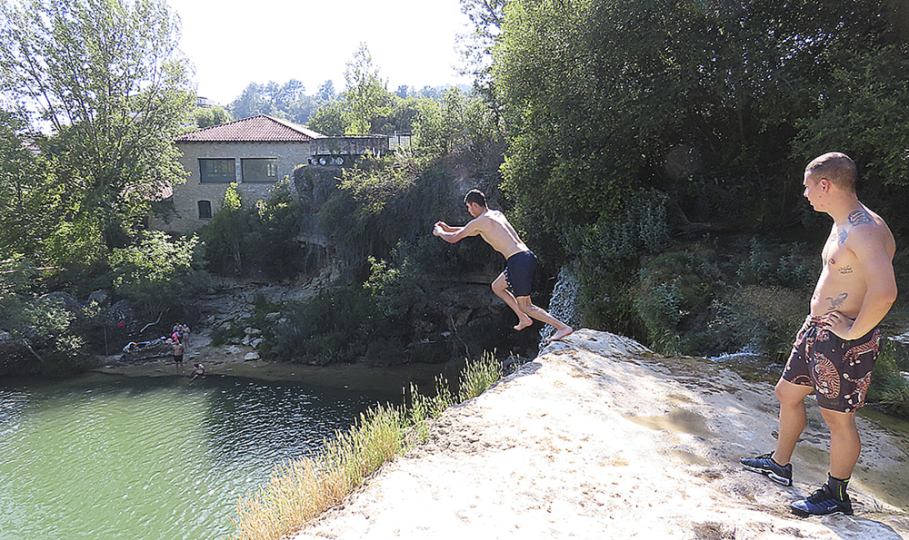 Dennis observa cómo se lanza Óscar desde lo alto de la cascada del Peñón, una práctica habitual.